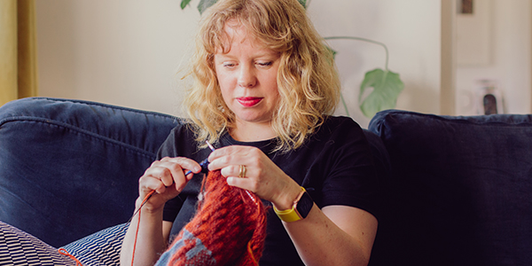 IOWHTS - Maker knitting sitting on a blue couch. 